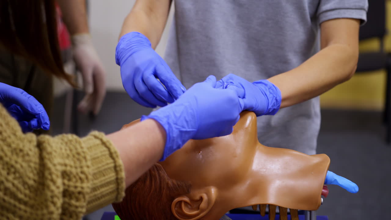 Training course in medical center. Medical instructing student to perform treatment procedure on a dummy head. Close-up.