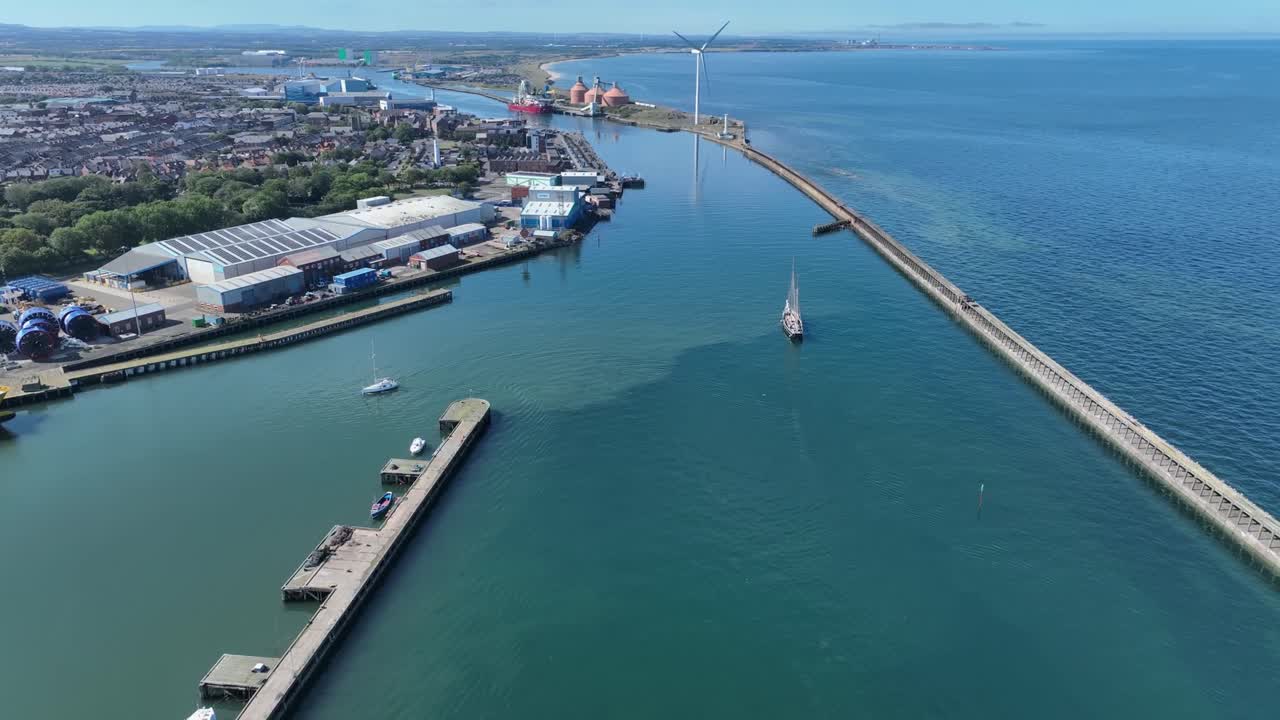Drone clip over Blyth Harbour with large wind turbine and tall ship sailing