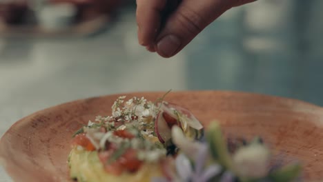 chef garnishes dish with spices and flowers