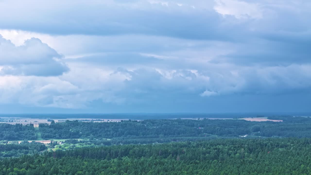 Moving powerful storm above woodland landscape, aerial time lapse view