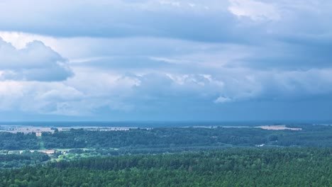 moving powerful storm above woodland landscape, aerial time lapse view