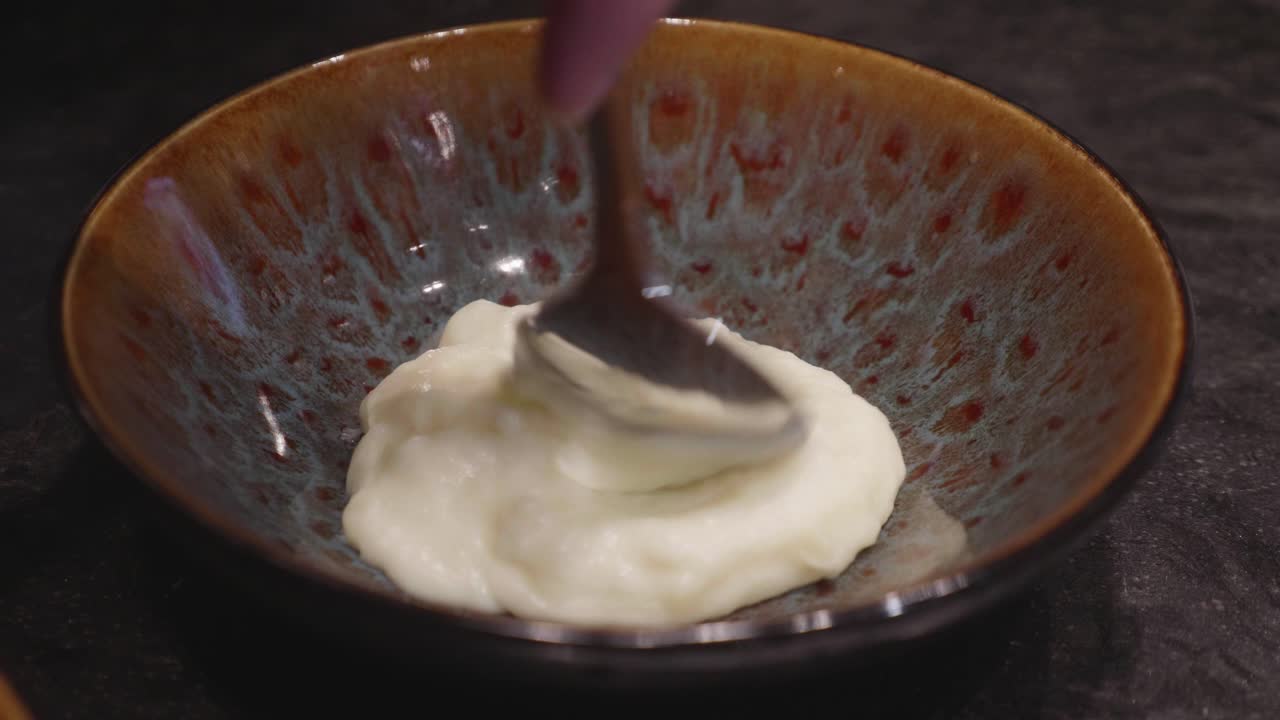 Chefs makes plating of meat and mashed potato dish, adding bits of green veggies nn top