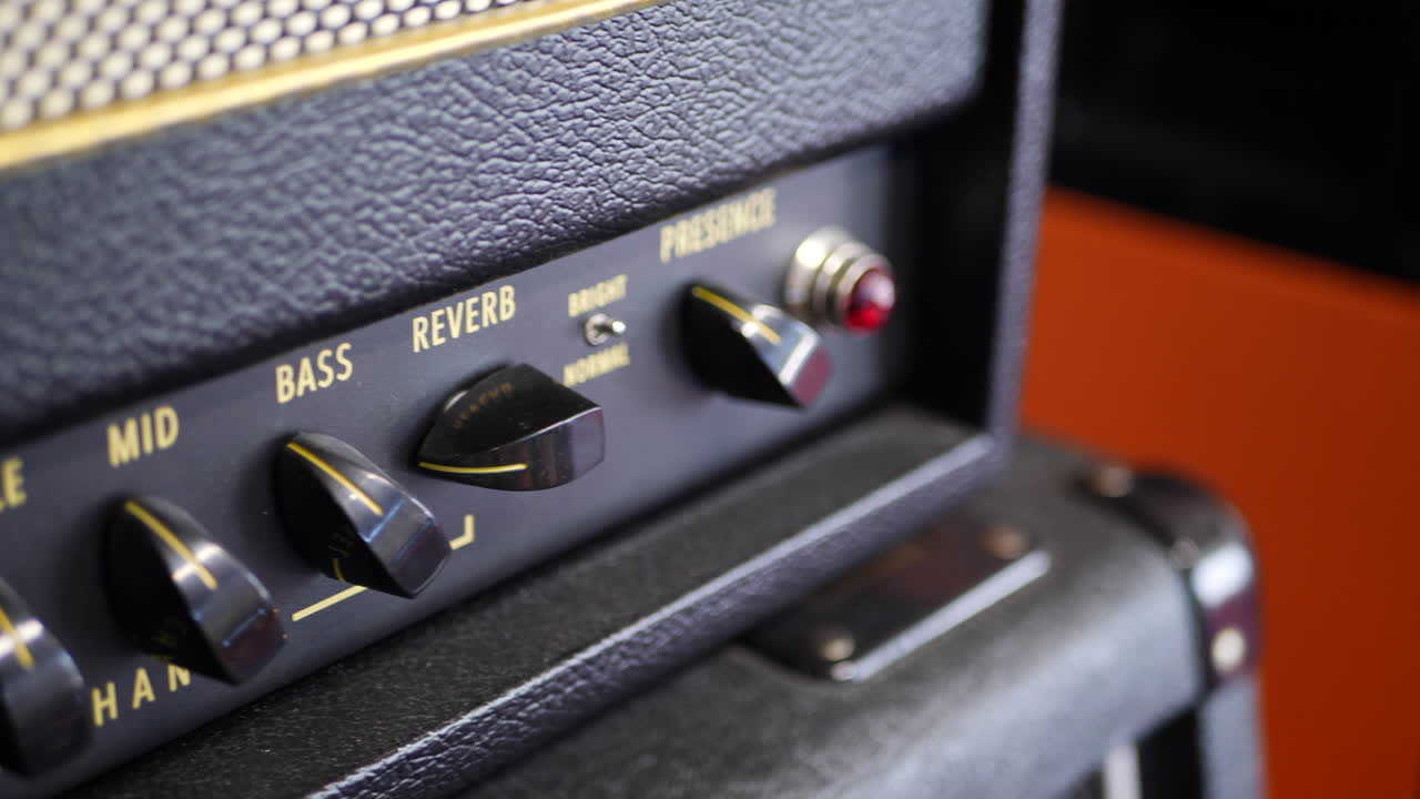 A vintage tube guitar amplifier with knobs and switches in a music studio for recording rock and roll