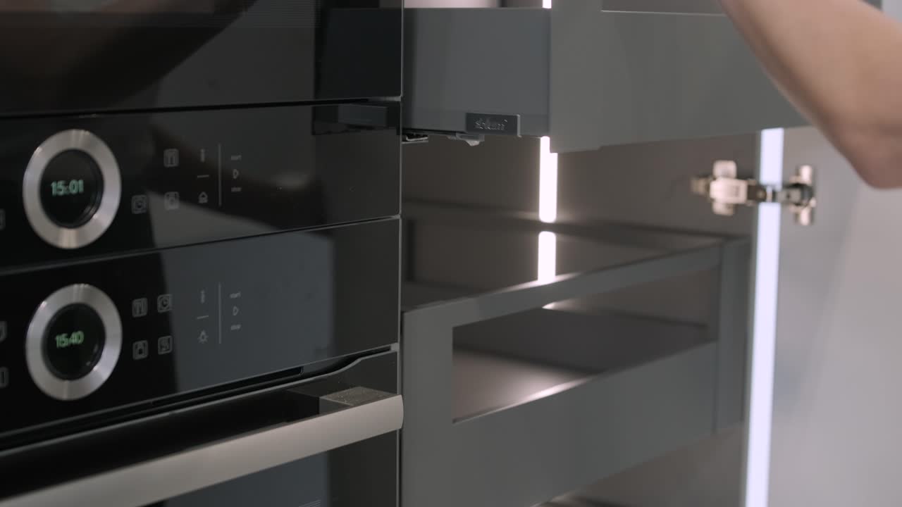 рука человека захвачена, открывая современный кухонный шкаф с классической латунистой ручкой, демонстрируя пересечение современных и традиционных элементов дизайна