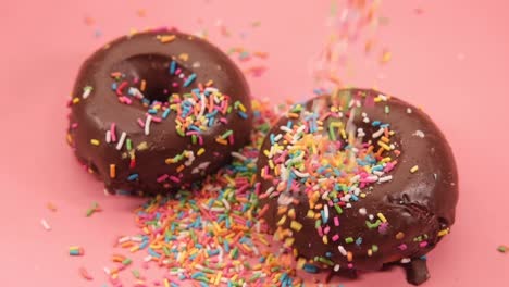 chocolate donuts with sprinkles on pink background