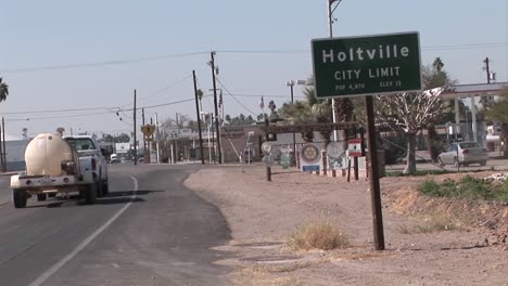 a car exits a parking lot and a cement truck drives by at the outskirts of a town