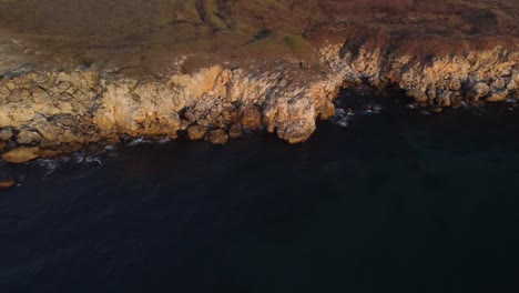 drone top down aerial view of waves splash against rocky seashore, background