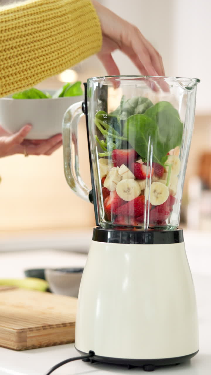 Aggiungere spinaci freschi a un frullatore con frutta per un frullato salutare