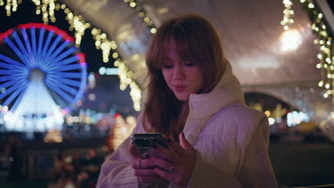 tourist looking cellphone illuminated luna park at night closeup. woman texting