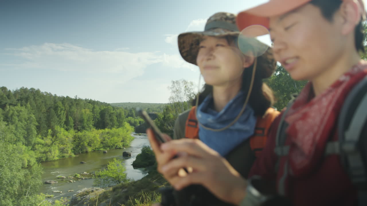 Asian Women Discussing Hiking Route on Phone