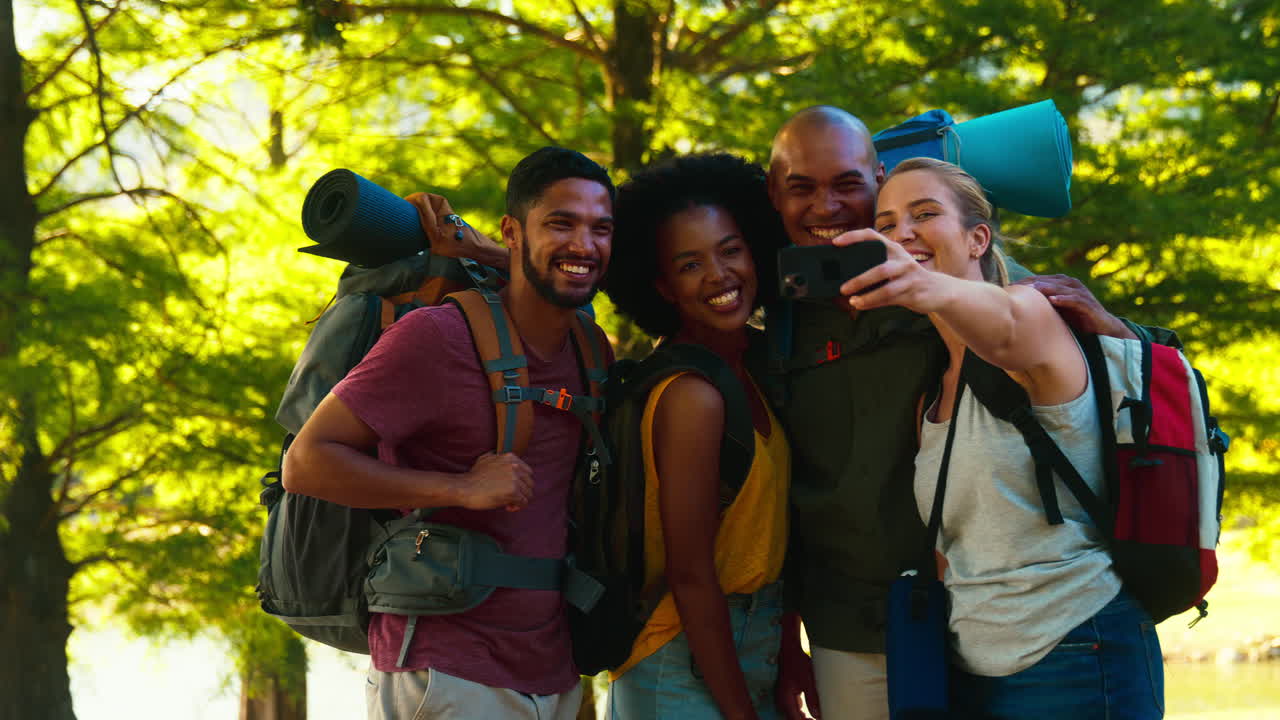 Gruppo di amici con zaini che posa per un selfie con il cellulare durante un'escursione in campagna in vacanza