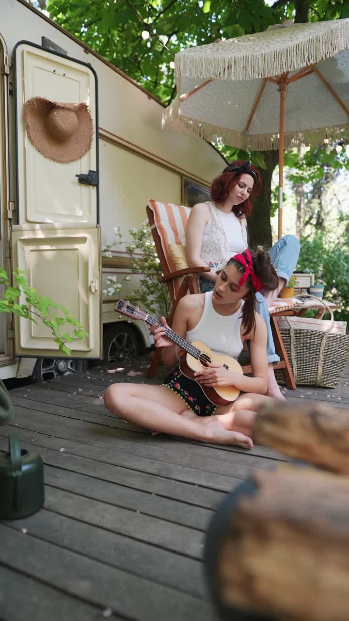 두 친구 가 캠핑 여행 에서 우쿨레 를 연주 하고 있다