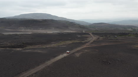 Vista-De-Pájaro-Coche-Conduciendo-Camino-De-Tierra-Viajando-En-Islandia-Turismo-Desierto.-Vista-Aérea-4x4-Suv-Coche-Explorando-Las-Tierras-Altas-En-El-Campo-Islandés-Descubriendo-La-Belleza-En-La-Tierra