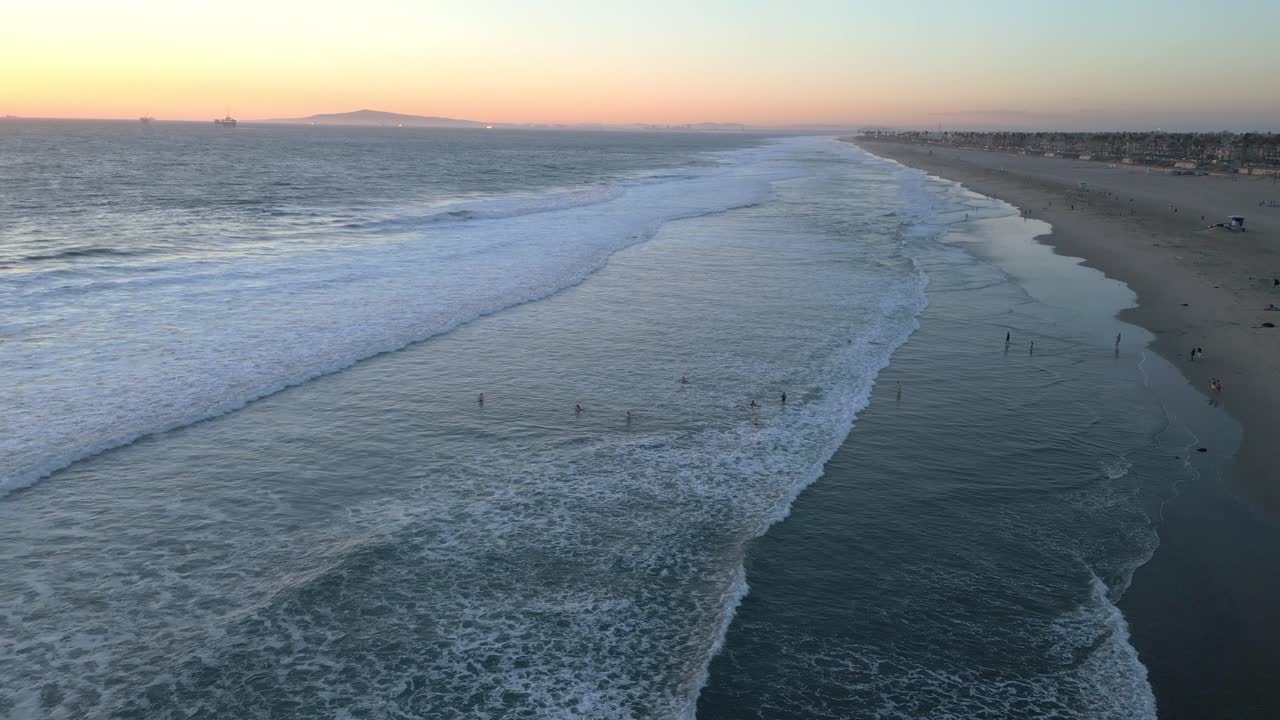Drone che vola sopra la tranquilla costa della California durante il tramonto a Huntington Beach.