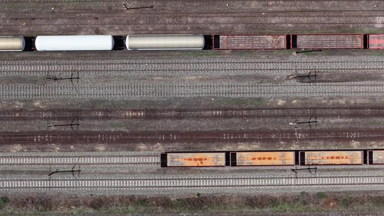 An aerial view captures a freight train transporting cargo across the railway network in Hungary, emphasizing industrial logistics and infrastructure.