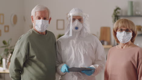 retrato de una pareja de ancianos y un médico en uniforme de protección en casa