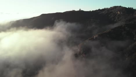 una foto aérea del cañón de topanga en malibu, california, mientras las nubes se mueven lentamente sobre la colina temprano en la mañana cuando sale el sol.