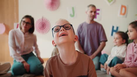 happy-Cheerful-albino-boy-in-round-glasses-laughs-and-smiles-against-of-his-first-lesson-in-preparation-for-school.-Portrait-of-an-albino-boy-at-his-first-lesson-at-school