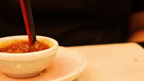 chopsticks stirring sauce in a small bowl