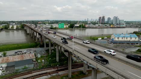 vehicles travel across the oak street bridge over the fraser river in richmond, british columbia, canada - aerial drone shot
