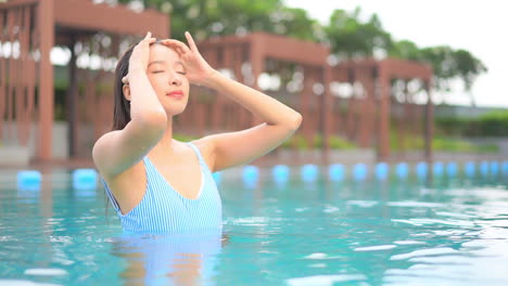 Joven-Mujer-Delgada-Y-Sexy-Acaricia-Su-Cabello-Mojado-Después-De-Nadar-En-La-Piscina-Del-Resort-Tropical,-Cámara-Lenta