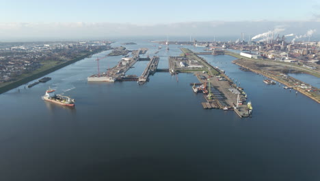 aerial of ship near ijmuiden sluis, the largest sea ship lock in the world - drone pulling back