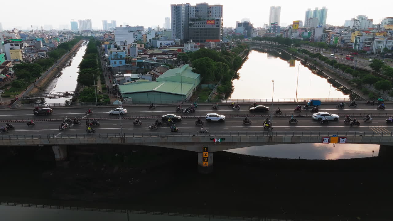 A breathtaking aerial shot captures a bustling city bridge bathed in the warm glow of the setting sun. Vehicles of all shapes and sizes flow smoothly across the bridge