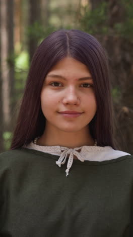 dark-haired girl in medieval dress smiles in woods, close-up