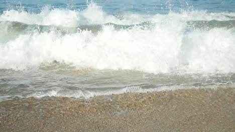 Small-waves-splash-when-hitting-the-shore-with-white-sand-in-summer