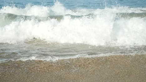 small waves splash when hitting the shore with white sand in summer