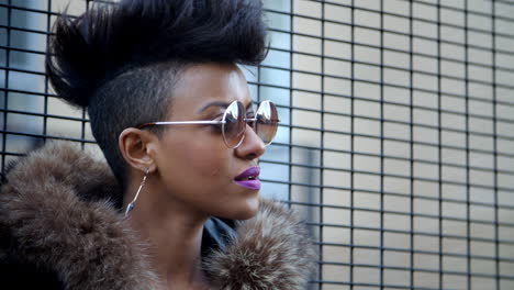 stylish fashion blogger stands by fence in urban street