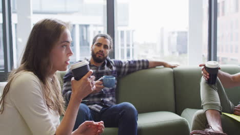 diverse group of business colleagues sitting on sofa drinking coffee and talking