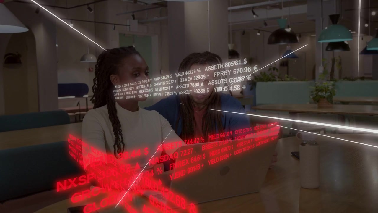 Financial ticker overlay appearing while male typing and female leaning, pointing, analyzing data