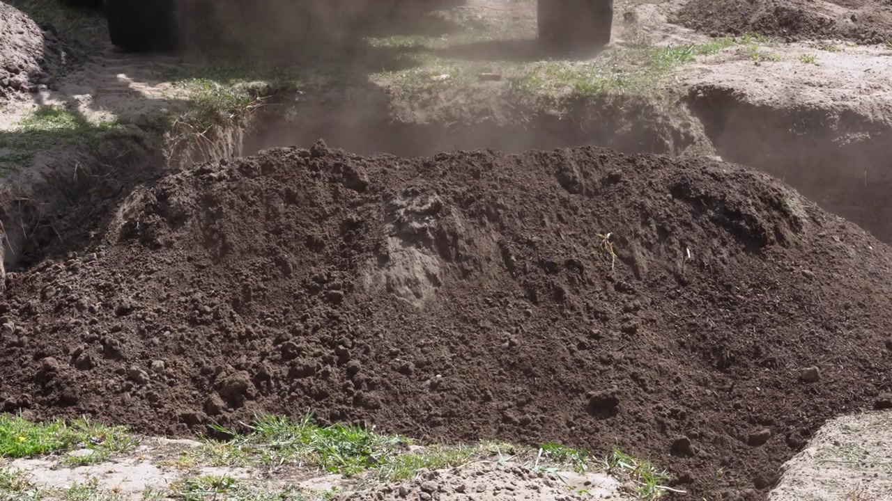 Una pala caricatrice frontale che scarica compost organico per creare un giardino della pioggia per la ritenzione e lo stoccaggio dell'acqua