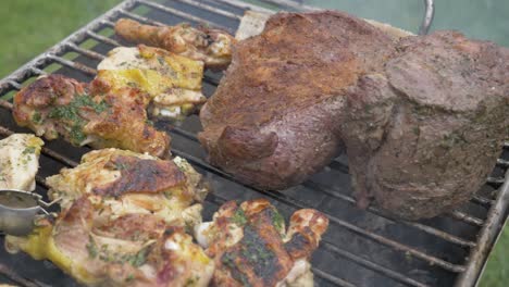 close shot of two people waiting for the meat to roast and then flipping it with tongs on barbeque