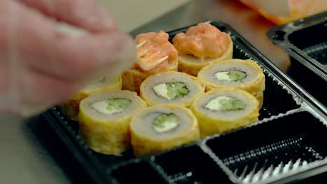 el chef decora rollos japoneses fritos cremosos con una tortilla