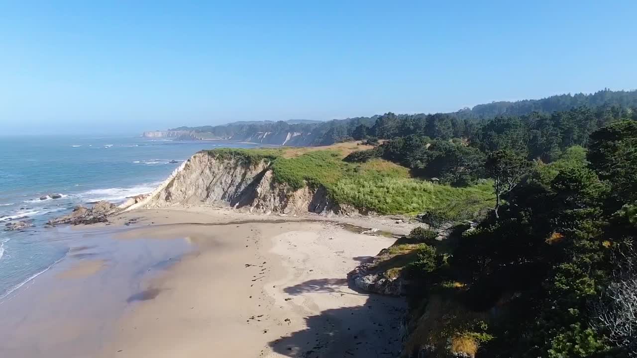 드론 촬영은 녹색 절벽, 모래 해안, 바다 파도의 혼합물을 보여줍니다. 캘리포니아의 보데가 만과 구알라 해안의 해안 풍경을 제공합니다.