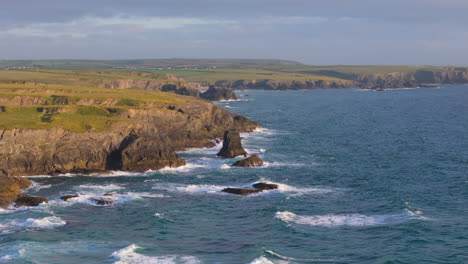 Waves-crashing-into-rugged-rocky-Cornwall-UK-coastline,-scenic-aerial-view