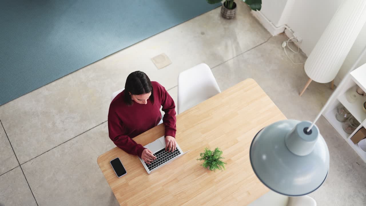 Young Woman Working on Laptop and Using Smartphone at Modern Table