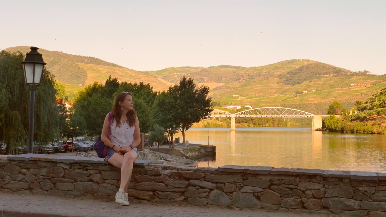 Ragazza seduta su un ponte accanto al fiume Douro