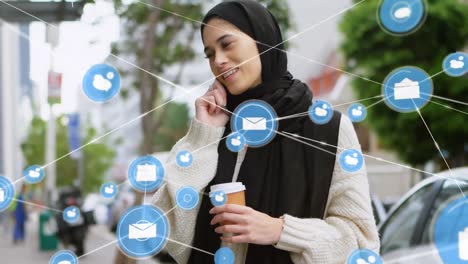 Animation-of-connected-icons-over-biracial-woman-wearing-hijab-with-coffee-talking-on-cellphone
