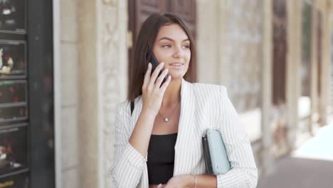 Hermosa-Joven-Mujer-De-Negocios-Caminando-Y-Hablando-Por-Un-Teléfono-Inteligente