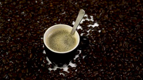 steady shot of a cup of coffee with a spoon, putting in sugar