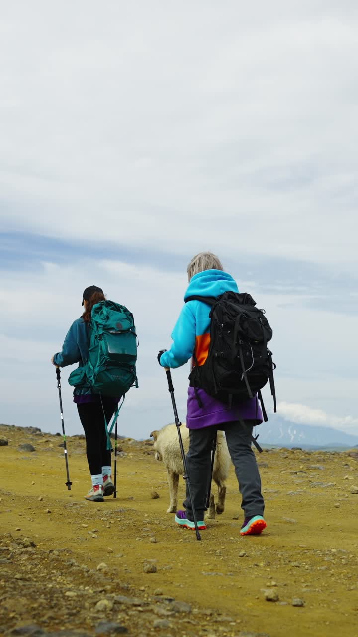 Due persone e un cane che fanno escursioni su un sentiero di montagna roccioso