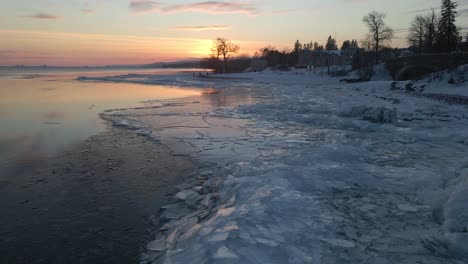 Dreieckige-Eisformationen-Häuften-Sich-An-Den-Ufern-Des-Oberen-Sees-Auf,-Wasserreflexionen-Während-Eines-Wintersonnenuntergangs