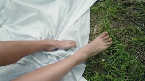 Woman-Bare-feet-on-white-fabric-against-grass