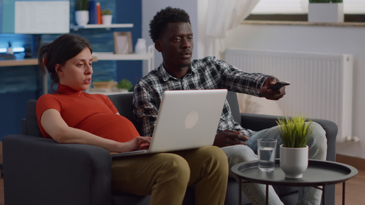 Pregnant interracial couple relaxing together at home