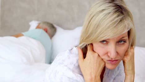 unhappy woman thinking while her husband is sleeping