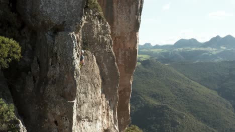 male rock climber clipping rope on sport route on cliff