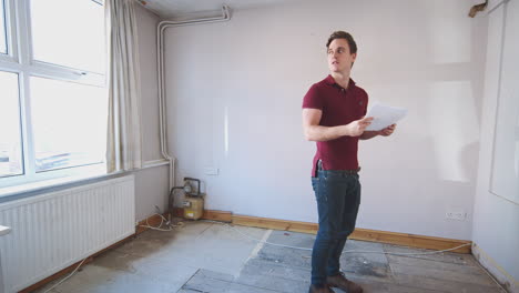 male first time buyer looking at house survey in room to be renovated